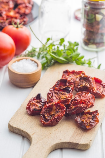 Gustosi pomodori secchi ed erbe aromatiche sul tagliere