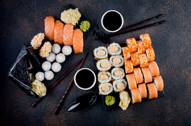 Gustosi rotoli di sushi con salse, bacchette, zenzero sul tavolo. Servizio di consegna cibo giapponese