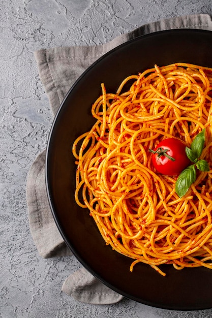 Gustosi spaghetti classici italiani appetitosi con salsa di pomodoro parmigiano e basilico sul piatto e ingredienti per cucinare la pasta sul tavolo di marmo bianco