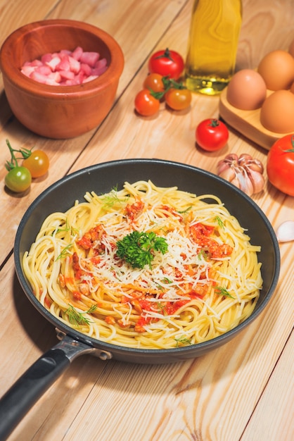 Gustosi spaghetti con salsa di pomodoro e carne in padella sul tavolo di legno.