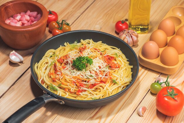 Gustosi spaghetti con salsa di pomodoro e carne in padella sul tavolo di legno.