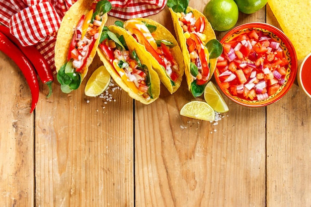 Gustosi tacos appetitosi con fagioli in salsa di pomodoro, verdure e salsa serviti su sfondo di legno Vista dall'alto con spazio di copia orizzontale