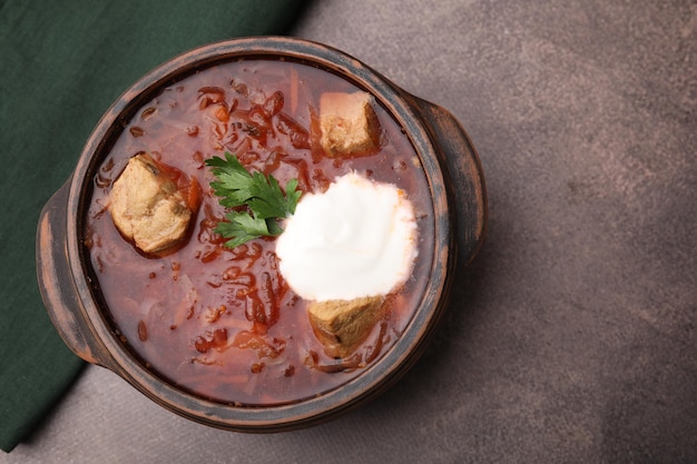 Gustoso borscht con panna acida in ciotola su tavolo testurizzato marrone vista dall'alto Spazio per il testo