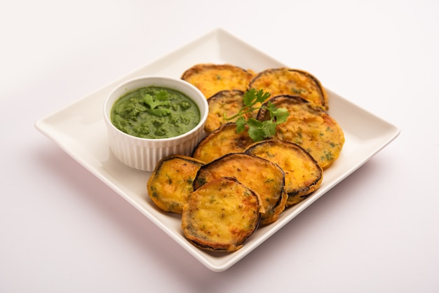 Gustoso Brinjal Pakora o frittelle di melanzane croccanti, snack indiano per l'ora del tè servito con chutney verde