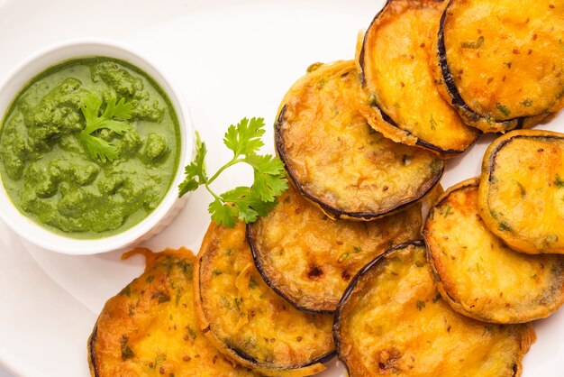 Gustoso Brinjal Pakora o frittelle di melanzane croccanti, snack indiano per l'ora del tè servito con chutney verde