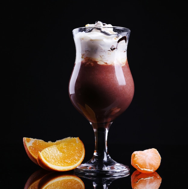 Gustoso dessert con salsa di cioccolato, panna e arancia, isolato su nero