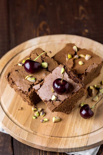 Gustoso dessert fatto in casa Brownie al cioccolato decorato con bacche e noci su vassoio di legno