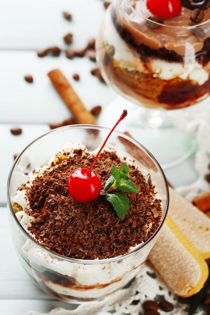 Gustoso dessert tiramisù in bicchieri su tovagliolo su fondo di legno