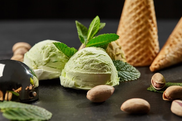 Gustoso gelato al pistacchio decorato con menta fresca e servito su una pietra di ardesia su fondo nero