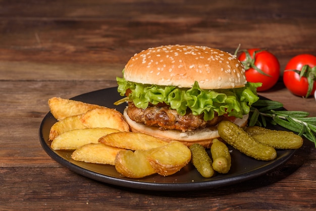 Gustoso hamburger alla griglia fatto in casa. Hamburger alla griglia deliziosi. Mestiere l'hamburger e le patate fritte del manzo sulla tavola di legno