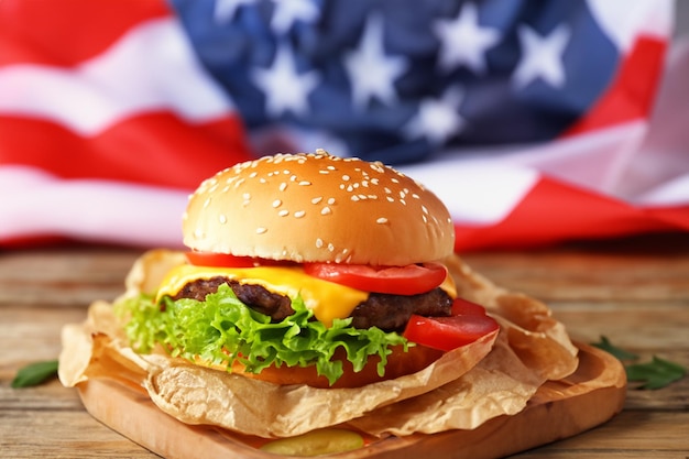 Gustoso hamburger con bandiera americana sulla tavola di legno