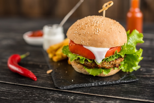 Gustoso hamburger con carne e verdure contro uno sfondo scuro. Fast food. Può essere usato come sfondo