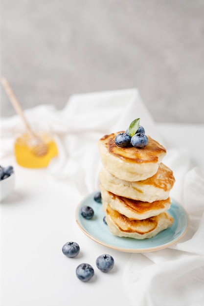 Gustoso pancake con mirtilli freschi e sciroppo impilati in pila su sfondo grigio