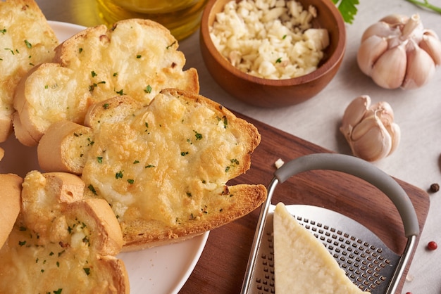 Gustoso pane fatto in casa con aglio, formaggio ed erbe aromatiche sul tavolo della cucina.