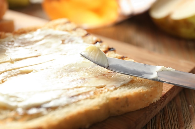 Gustoso pane tostato con burro su tavola di legno, primo piano