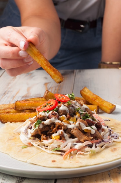 Gustoso pranzo con carne e verdure su tortillas e patatine fritte