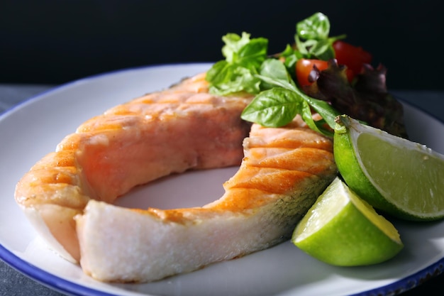 Gustoso salmone alla griglia con lime e insalata sul tavolo da vicino