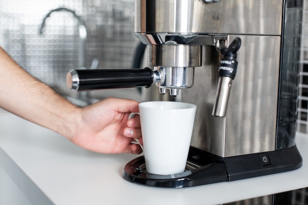 Guy prepara delizioso caffè aromatico in una macchina da caffè. Un modo semplice per fare il caffè