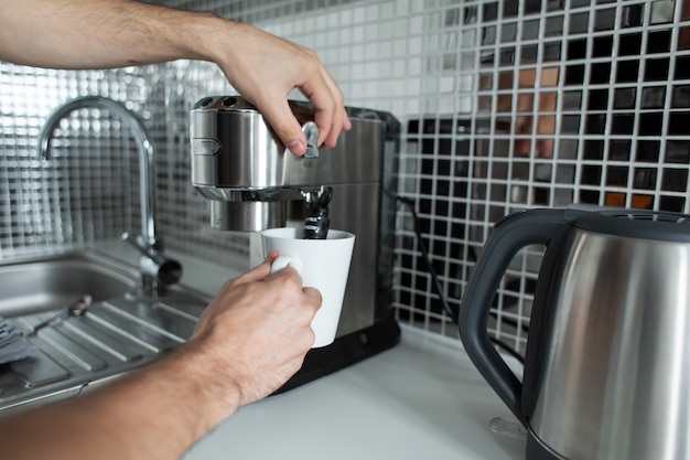 Guy prepara delizioso caffè aromatico in una macchina da caffè.