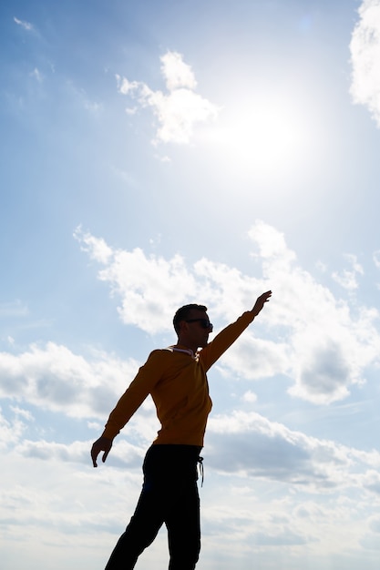 Guy turista freelance su uno sfondo di cielo azzurro con nuvole bianche, luminosa giornata di sole, natura e libertà umana