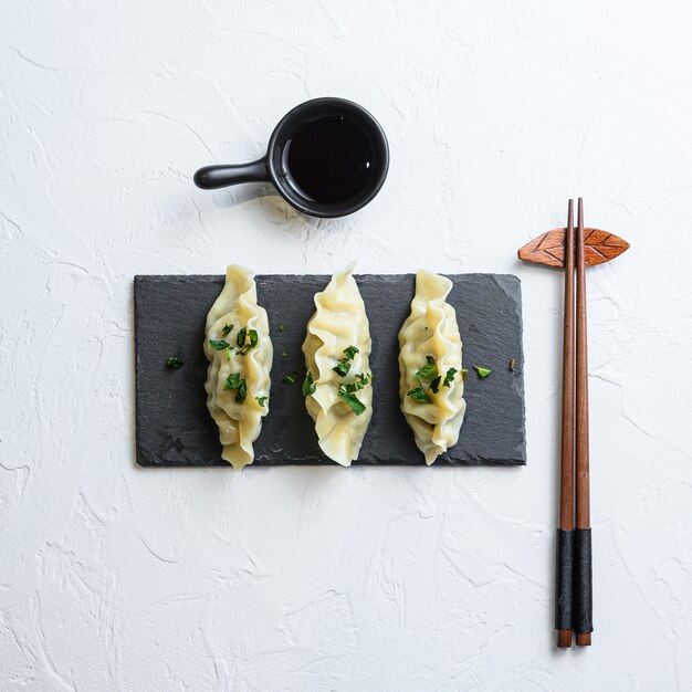 Gyoza giapponese o snack di gnocchi con salsa di soia cibo asiatico su sfondo bianco vista dall'alto