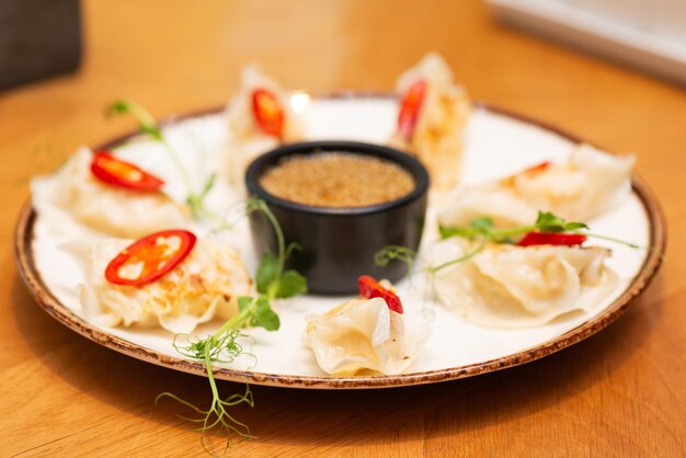 Gyoza o gnocchi fritti giapponesi con microverdi di peperoncino e salsa in un piatto in un ristorante