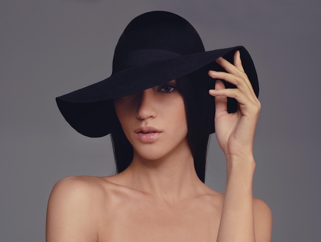 Ha bellezza e stile Foto in studio di una bella donna che indossa un cappello su uno sfondo grigio