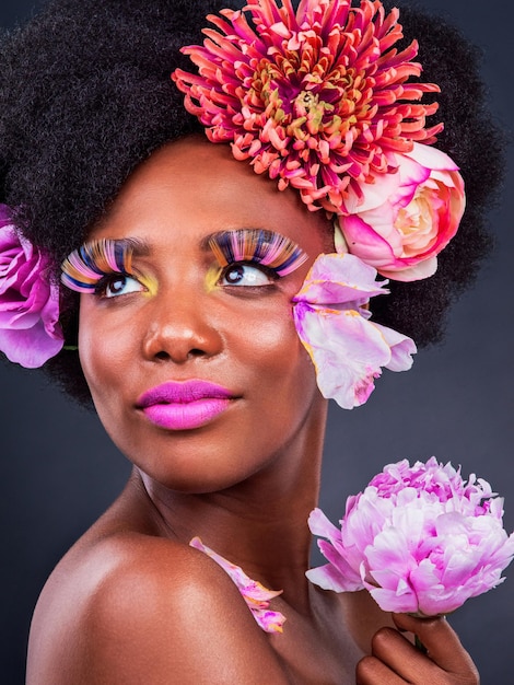 Ha fiori tra i capelli e magia nei suoi occhi Studio shot di una bella giovane donna in posa con fiori tra i capelli