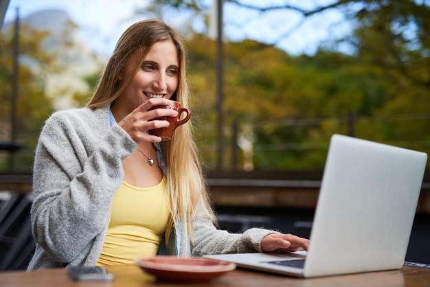 Ha un'ottima idea per il suo prossimo post sul blog Foto ritagliata di una giovane donna attraente che usa il suo laptop in una caffetteria all'aperto