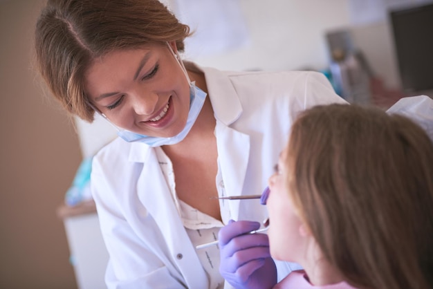 Ha una grande esperienza in odontoiatria pediatrica Inquadratura ritagliata di un dentista che esamina i denti di una bambina