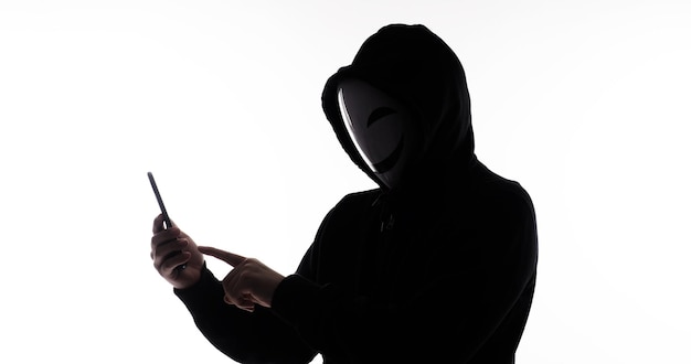 Hacker Anonymous e maschera facciale con smartphone in mano