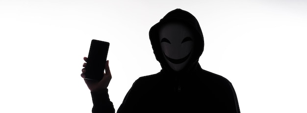 Hacker Anonymous e maschera facciale con smartphone in mano