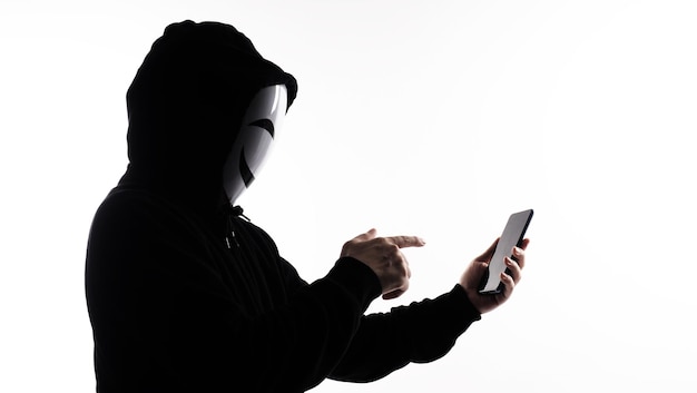 Hacker Anonymous e maschera facciale con smartphone in mano