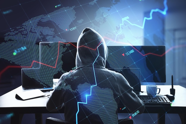 hacker at desk using computers with creative glowing blue map hologram with chart and grid on blurry office interior background economy hacking world and stock concept double exposure
