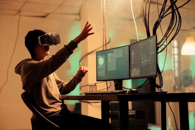 Hacker che codifica malware negli occhiali VR, hackera database nel metaverso, ruba informazioni sulla privacy, violazione di dati. Attacco informatico nella realtà virtuale, criminale Internet che irrompe nel server online