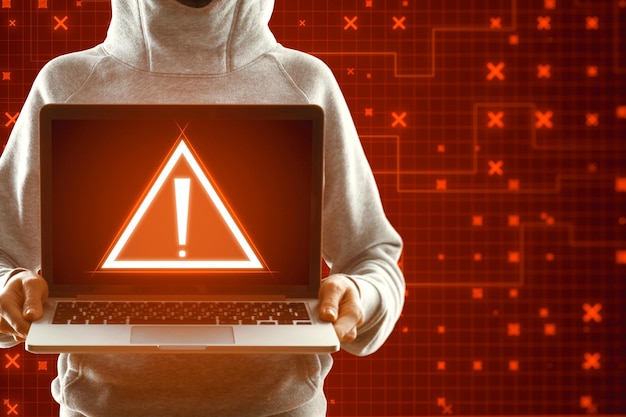 Hacker con laptop con allarme di sicurezza rosso creativo sullo sfondo sfocato Concetto di frode e pericolo