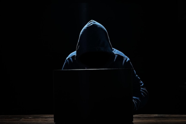 Hacker con laptop si siede a un tavolo e codice binario astratto Business vita minaccia programmi virtuali