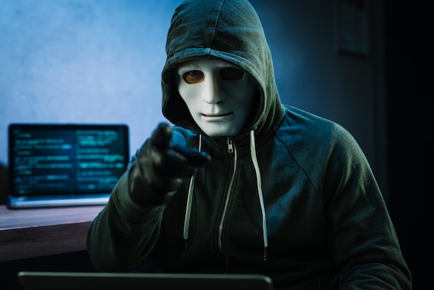 Hacker con maschera davanti al computer portatile