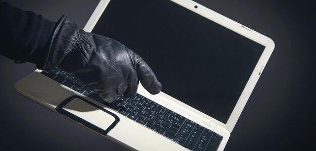 Hacker con un guanto di pelle con un computer