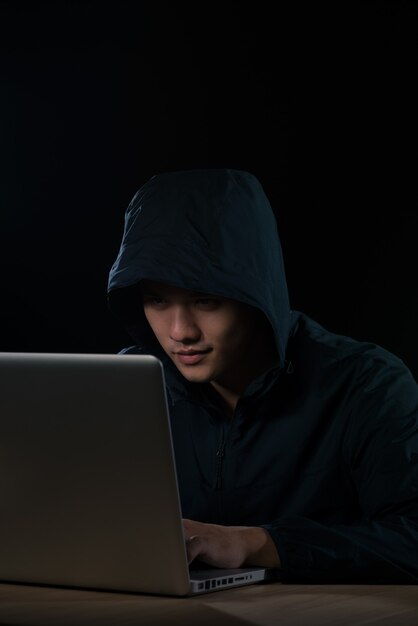 hacker in a dark hoody sitting in front of a notebook. computer privacy attack
