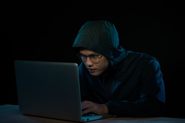 hacker in a dark hoody sitting in front of a notebook. computer privacy attack