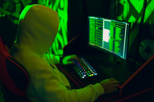 Hacker in felpa con cappuccio che lavora sul sito del codice degli hack sul personal computer Concetto di guerra e attacco informatico