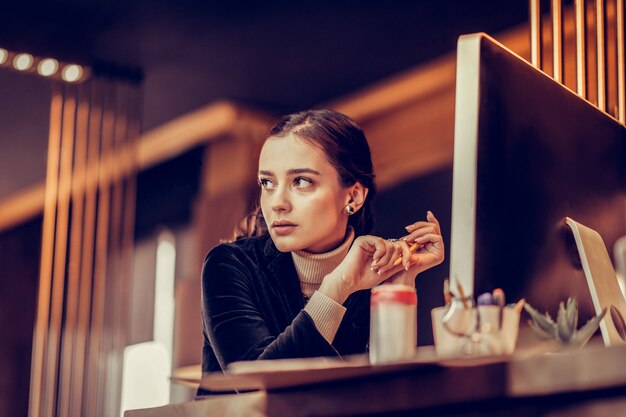 Hai bisogno di pensare. Allegra donna seduta al suo posto di lavoro e la creazione di un piano d'azione