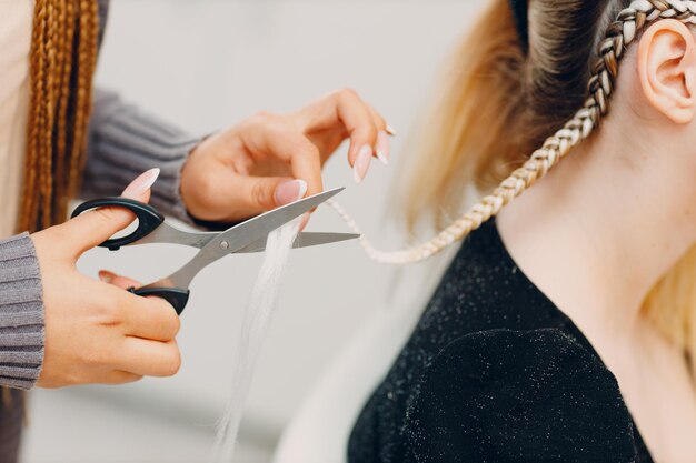 Hairstylist intrecciato afro trecce trecce capelli del cliente femminile nel salone di barbiere