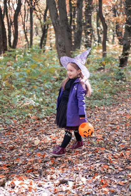 Halloween. bambina carina in costume da strega con jack o lantern divertendosi all'aperto