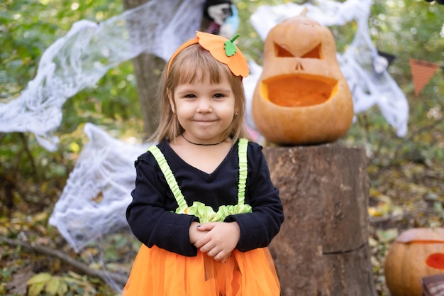 Halloween. bambina carina in costume da zucca divertendosi, celebrando Halloween all'aperto