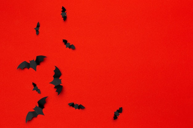Halloween e concetto della decorazione - pipistrelli di carta che volano sul fondo rosso