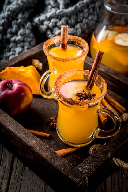 Halloween, Ringraziamento. Bevande e cocktail tradizionali autunnali, invernali. Sangria piccante di zucca calda, con mela, cannella, anice. Nel vassoio, tavolo in legno rustico, tazze di vetro. Messa a fuoco selettiva copia spazio