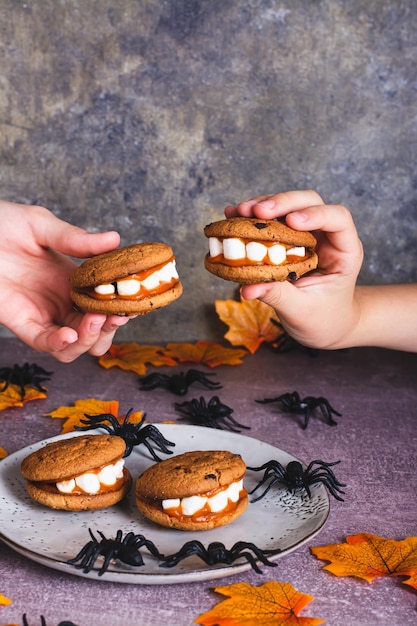 Halloween tratta i biscotti con denti di marshmallow nelle mani dei bambini vista verticale