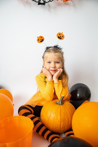 Halloween. Una ragazza con un vestito arancione appoggiò le mani su una zucca. Cartolina con spazio per la copia.